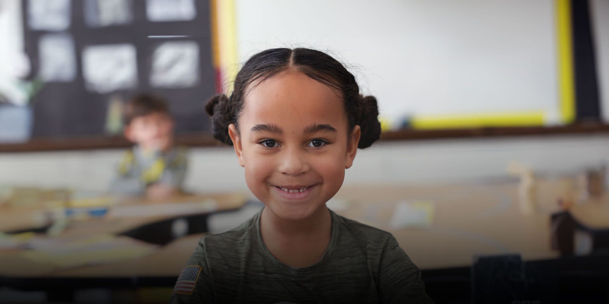 Smiling student sitting at a table in a classroom.