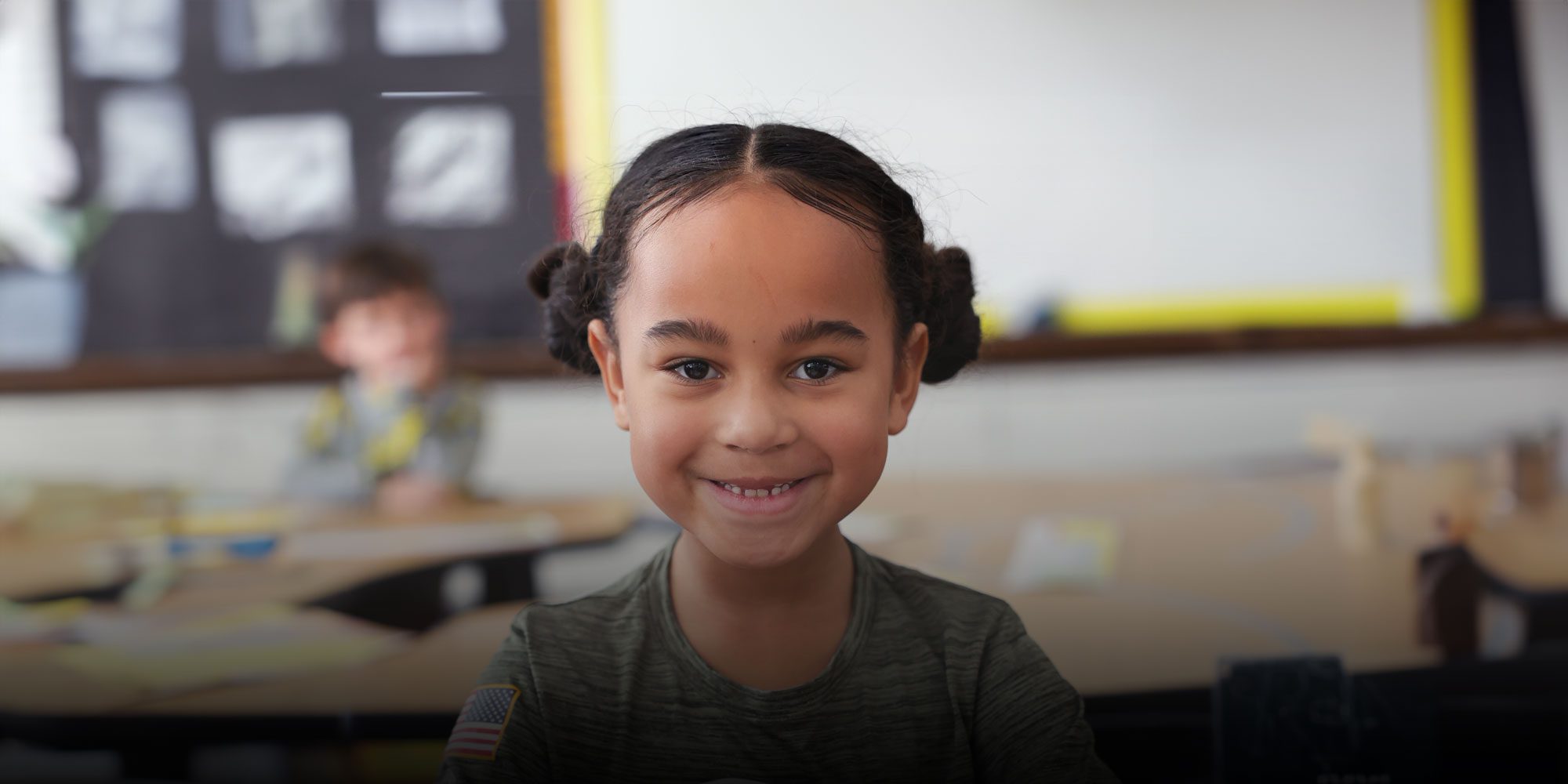 Smiling student sitting at a table in a classroom.