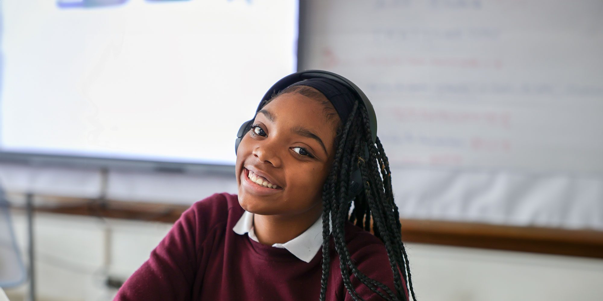 Smiling student wearing headphones in a classroom.