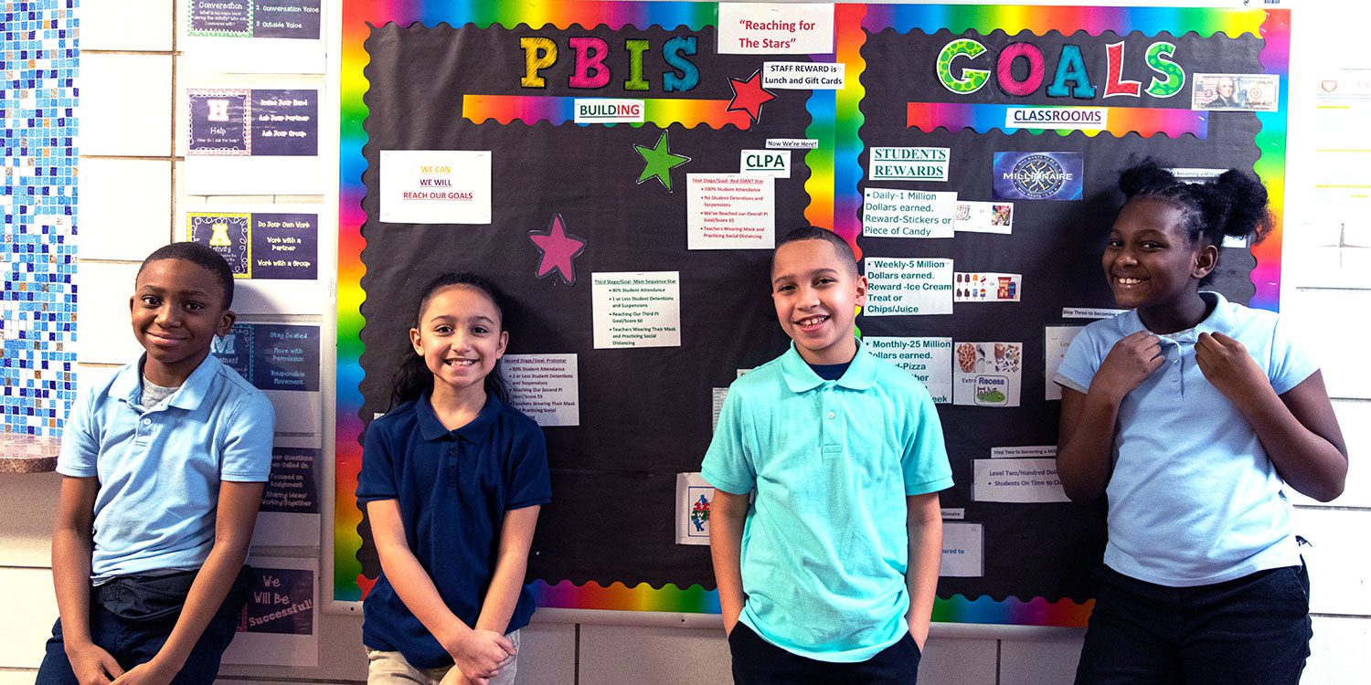 Smiling students standing in hallway.